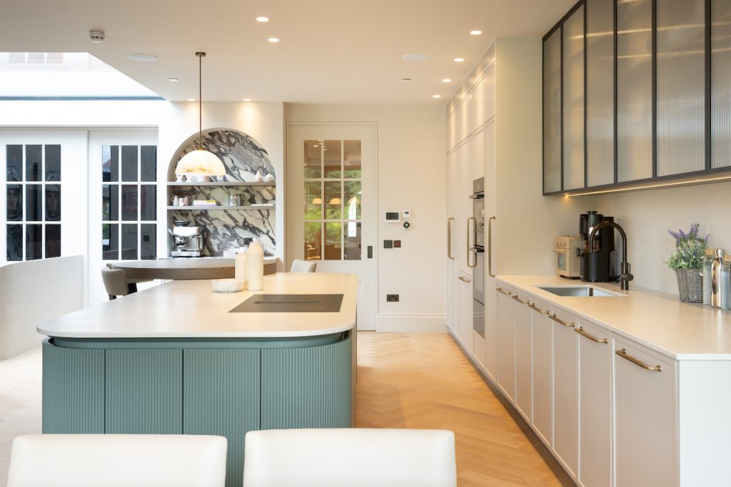 Custom rounded fluted joinery above full-height kitchen cabinets, designed to discreetly conceal an air-conditioning unit.