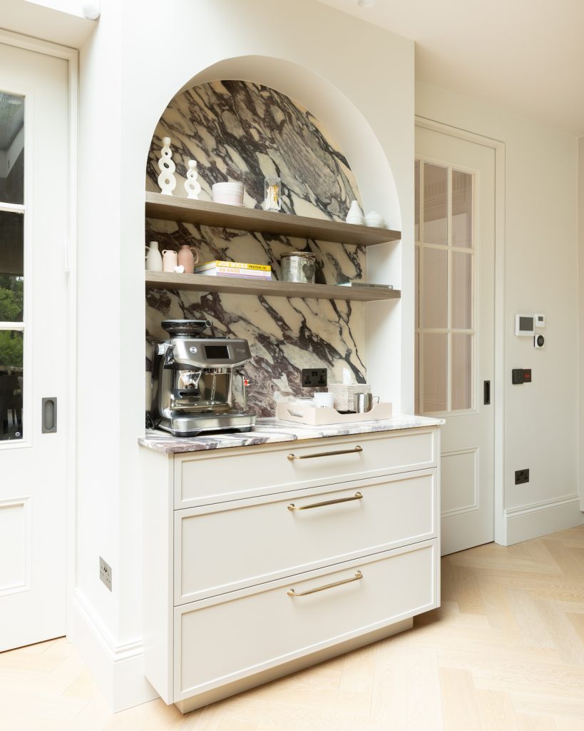 Bespoke coffee station with dramatic veined marble, curved surround and open display shelves in the Oakhill kitchen.