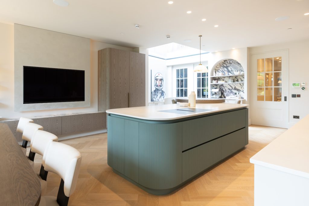 Bespoke curved kitchen island with muted blue fluted cabinetry and a light-toned worktop in a Hampstead family home.